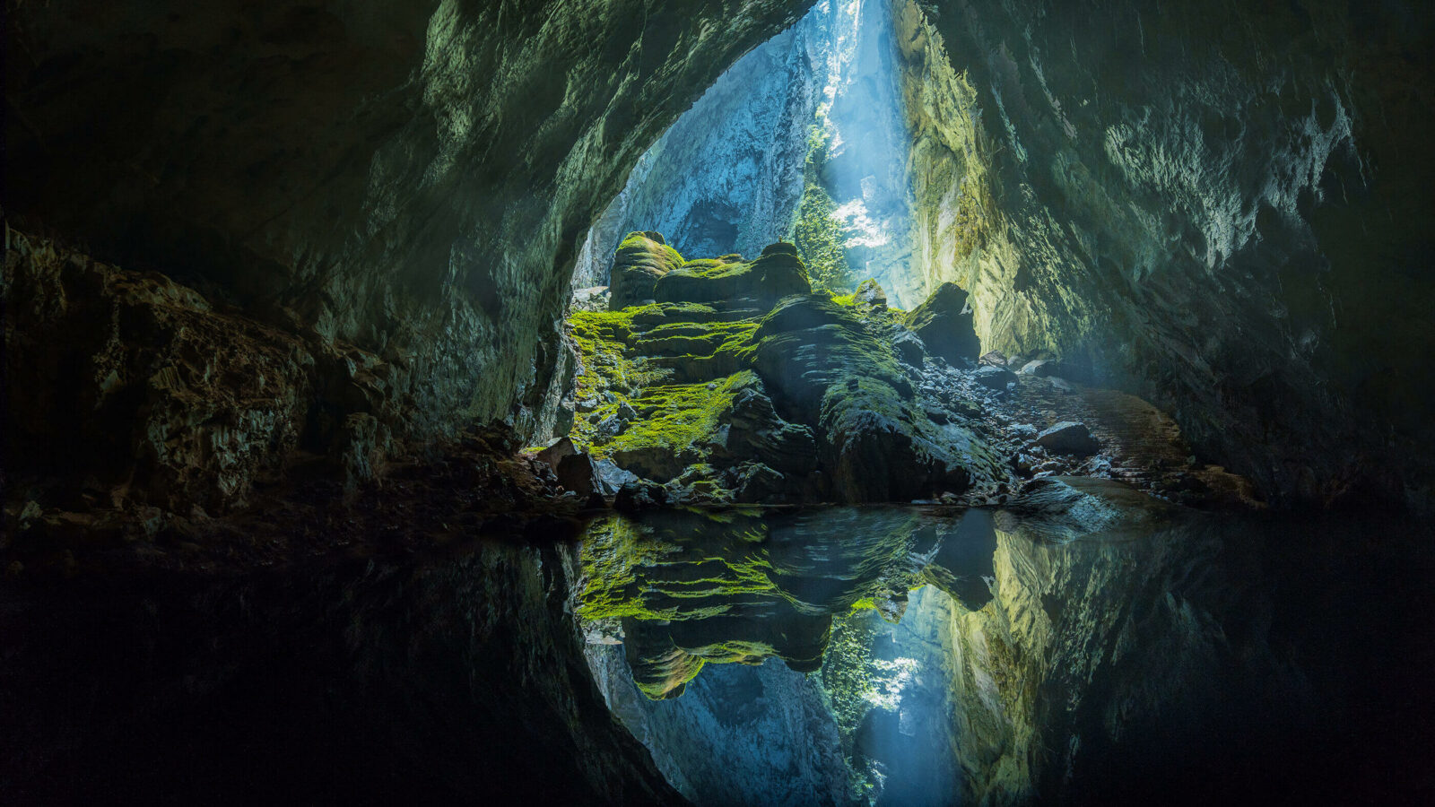 A large cave opening with water inside.