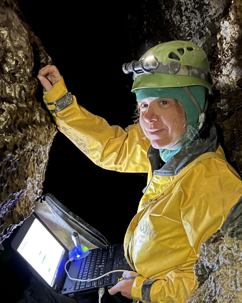 Sarah Arpin in a cave with computer collecting samples